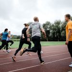 man coaching runners on a running track