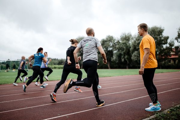 man coaching runners on a running track